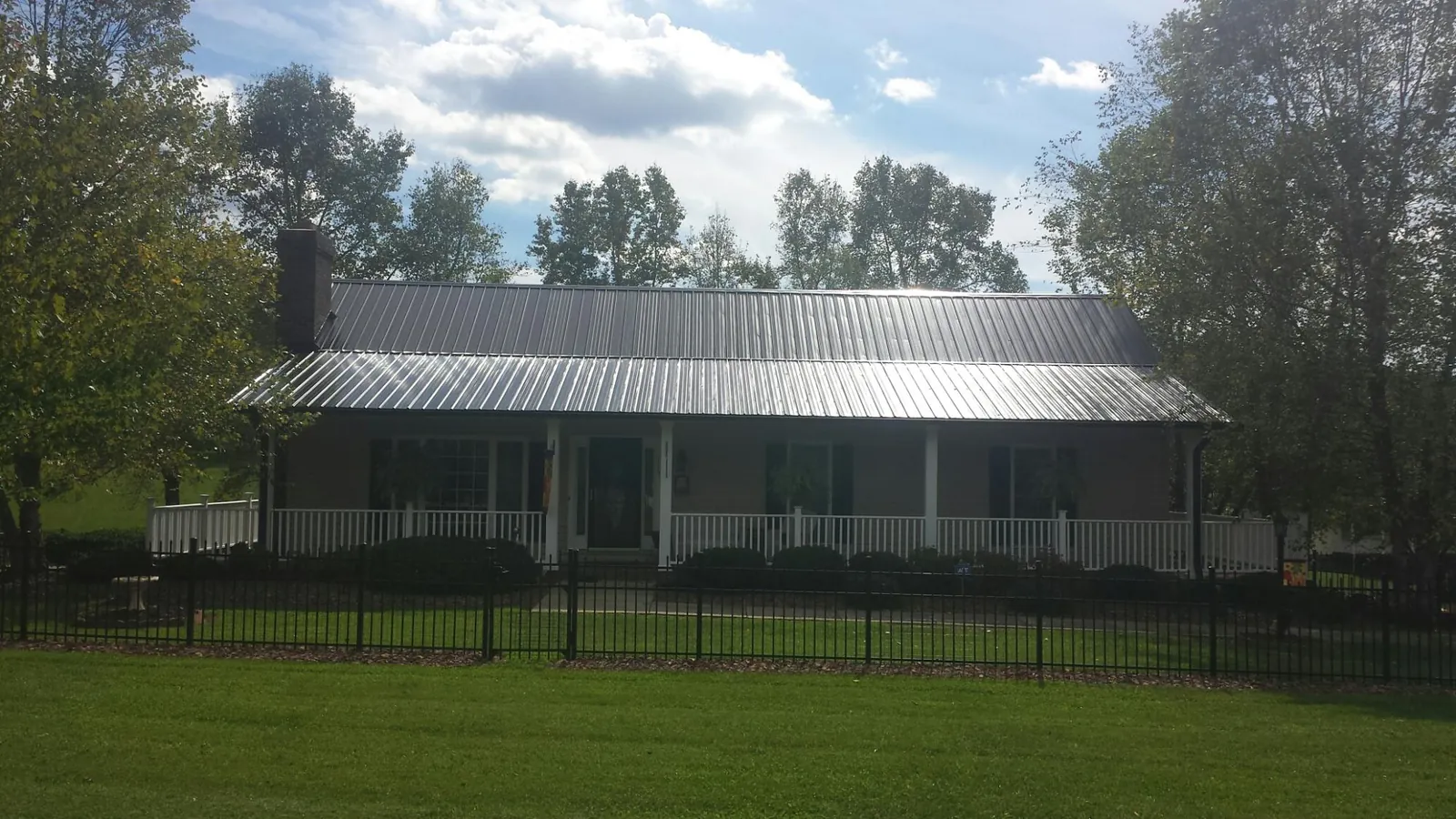Gray metal roof on a brick ranch with a full width front porch — Gutter Guard Installation work by our crew in Delta