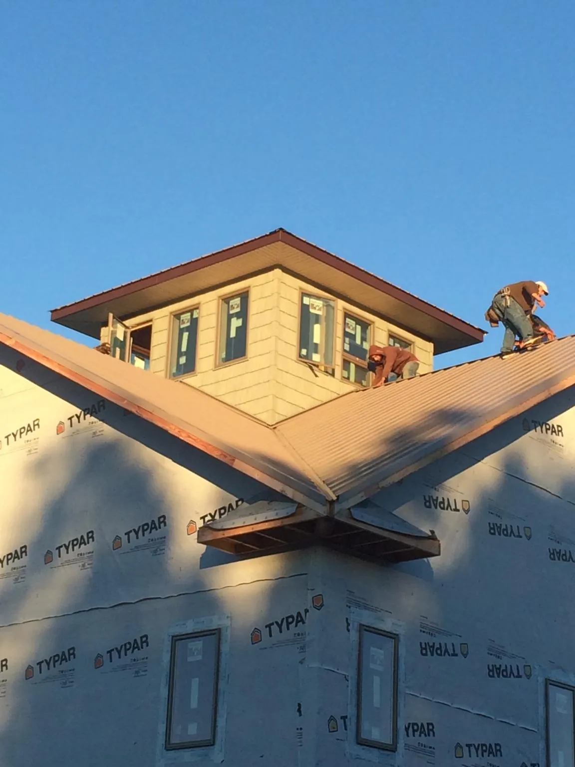 Roofers working around a rooftop cupola on a new metal roof at sunset — Roof Waterproofing in Delta by Roofing Brothers